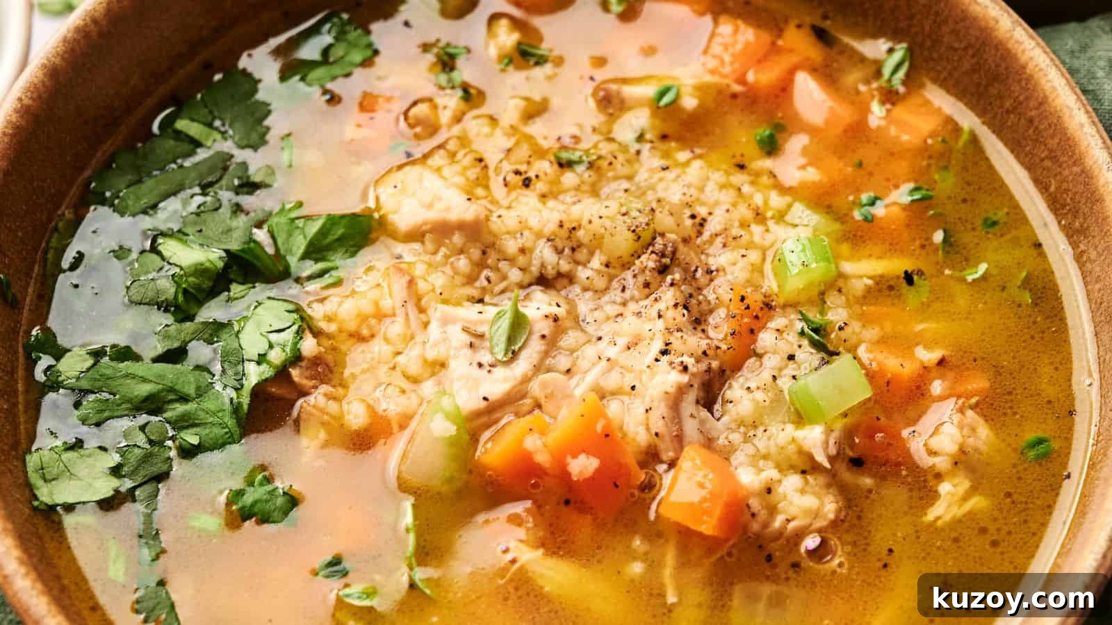 33 Must-Bring Thanksgiving Potluck Recipes for Every Year 14 A bowl of chicken soup with rice, carrots, celery, herbs, and pepper sprinkled on top.