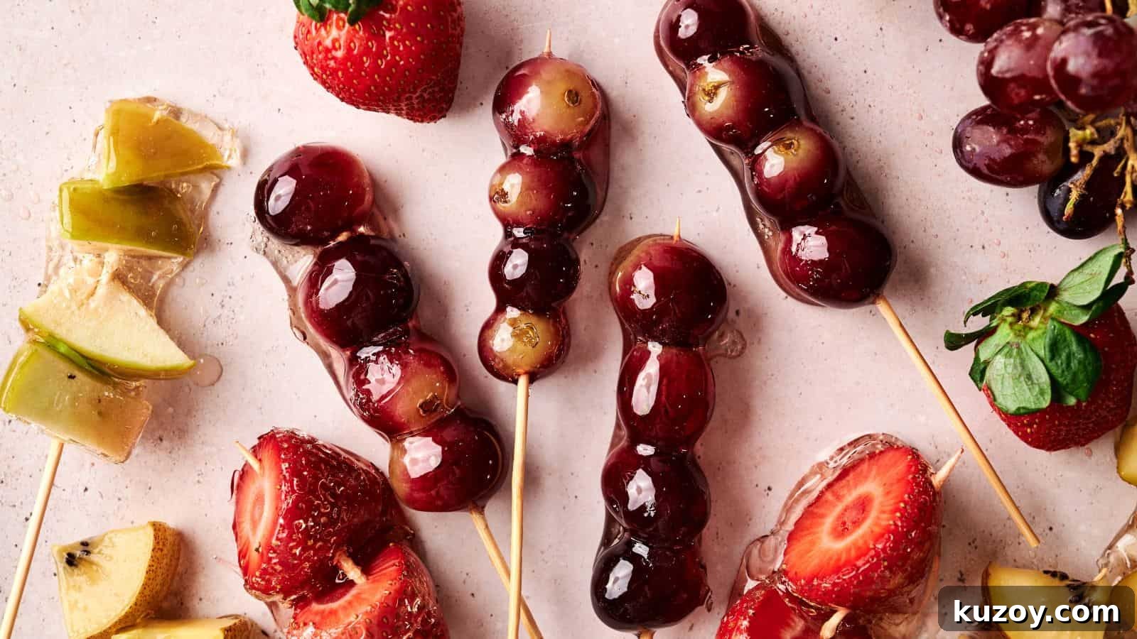 33 Must-Bring Thanksgiving Potluck Recipes for Every Year 18 Skewers of grapes and strawberries coated in a shiny glaze are arranged on a light surface with loose fruit pieces nearby.