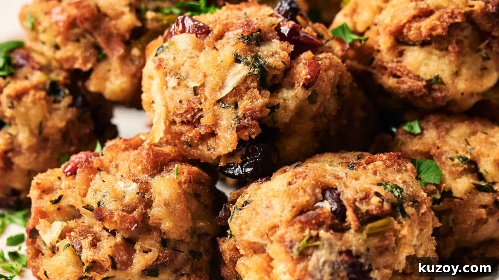 33 Must-Bring Thanksgiving Potluck Recipes for Every Year 19 Close-up of several stuffing balls containing herbs and dried cranberries, garnished with fresh parsley.