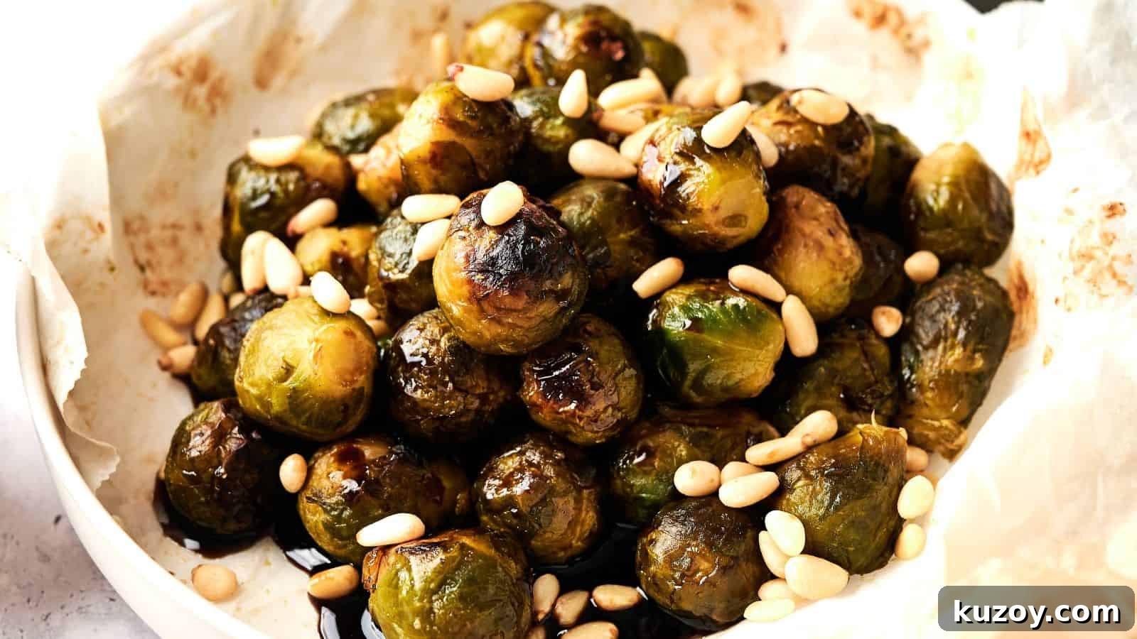 33 Must-Bring Thanksgiving Potluck Recipes for Every Year 24 A plate of roasted Brussels sprouts topped with pine nuts on parchment paper.