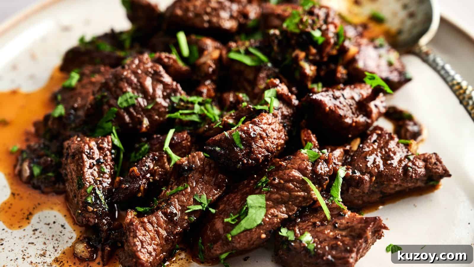 33 Must-Bring Thanksgiving Potluck Recipes for Every Year 26 Close-up of cooked beef chunks garnished with chopped herbs on a plate with a spoon nearby.