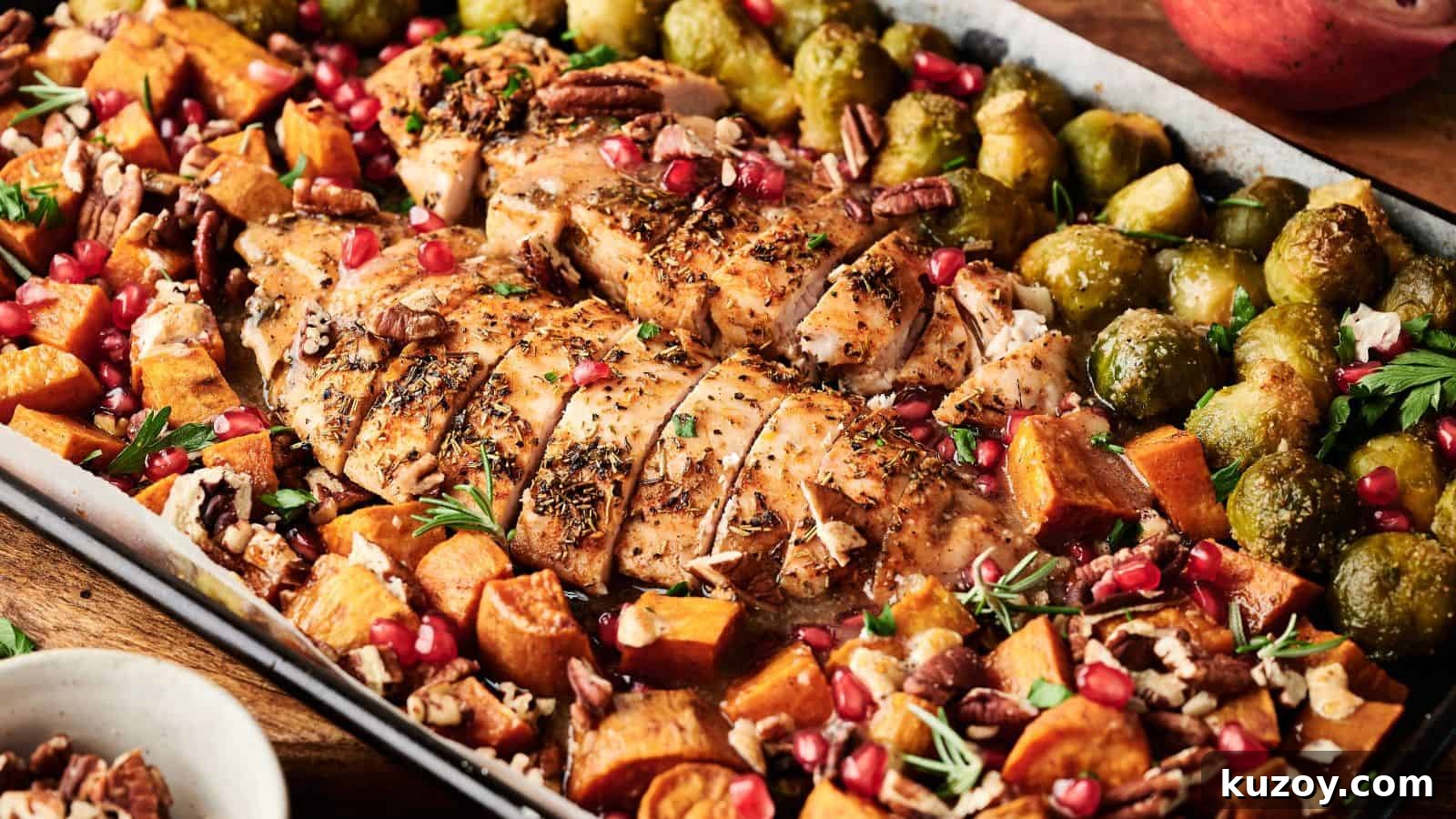 33 Must-Bring Thanksgiving Potluck Recipes for Every Year 4 Sheet pan meal with sliced roasted chicken breast, brussels sprouts, sweet potatoes, pecans, and pomegranate seeds, garnished with herbs.