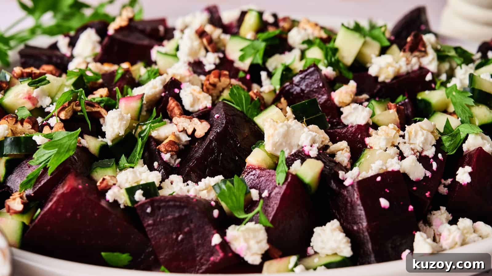 33 Must-Bring Thanksgiving Potluck Recipes for Every Year 9 A close-up of a salad featuring chopped beets, cucumber, feta cheese, walnuts, and fresh herbs on a white plate.