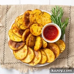 An overhead image of cottage fries arranged on a plate with ketchup in a small bowl and rosemary on the side.