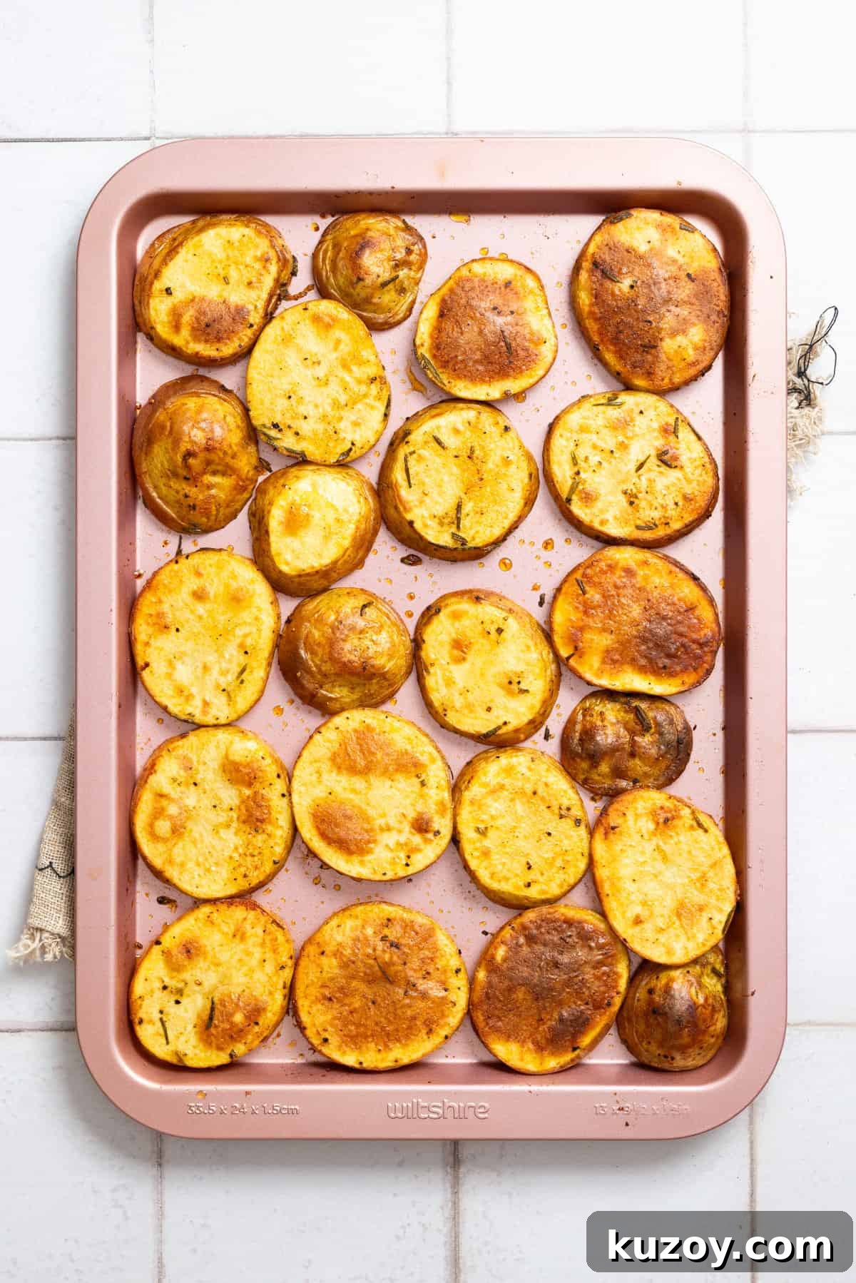 An overhead image of baked cottage fries spread out on a baking sheet.