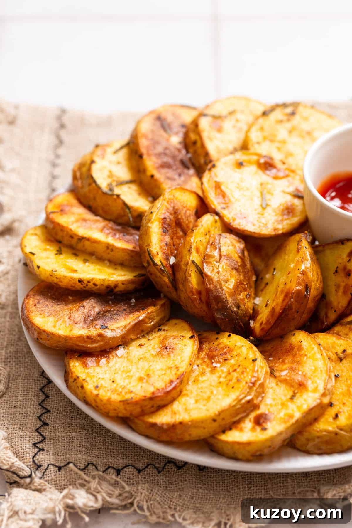 An image of cottage fries arranged on a plate with a small bowl of ketchup on the side.