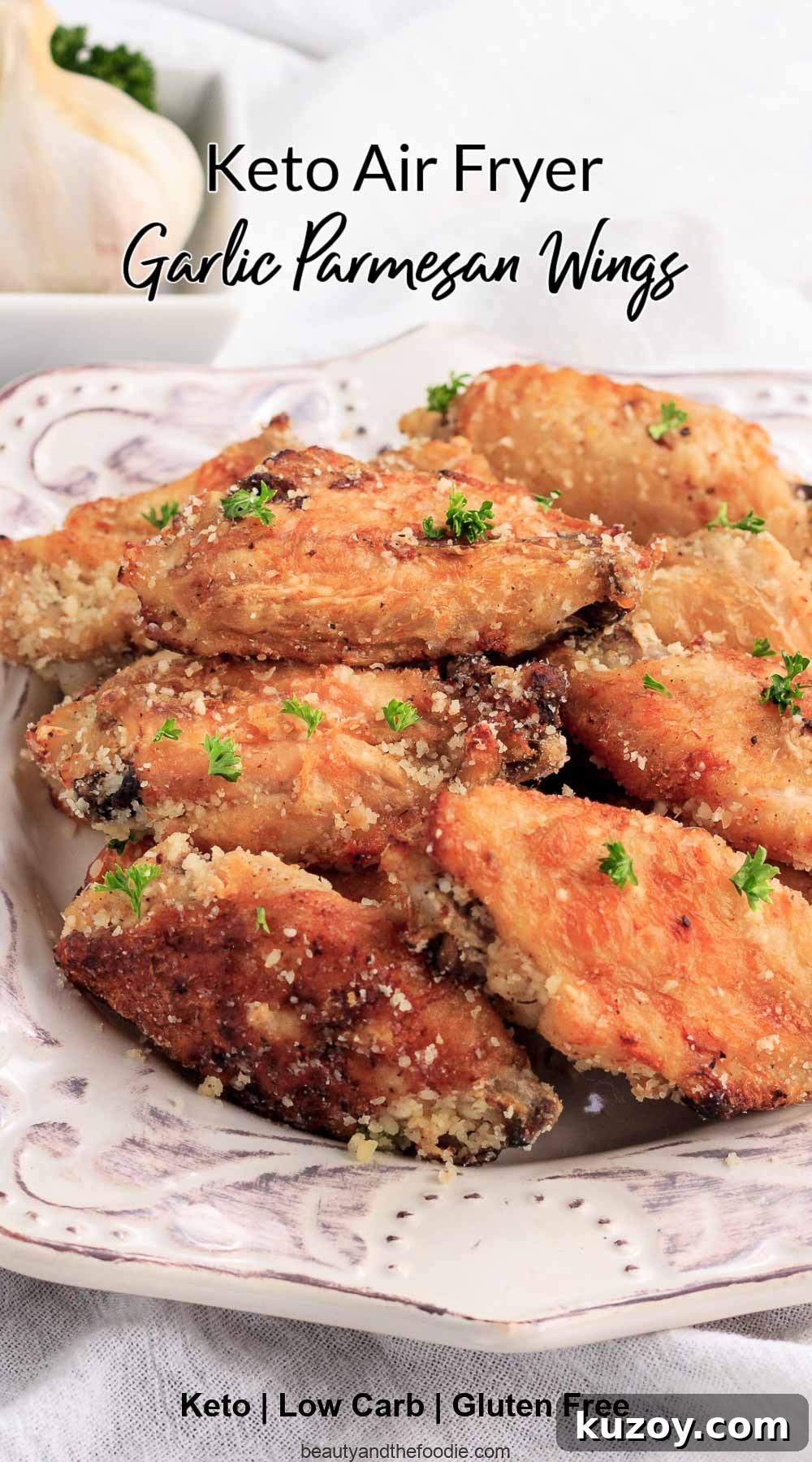Keto Garlic Parmesan Wings in the Air Fryer 3 A plate of garlic parmesan chicken wings with a bulb of garlic in the background.