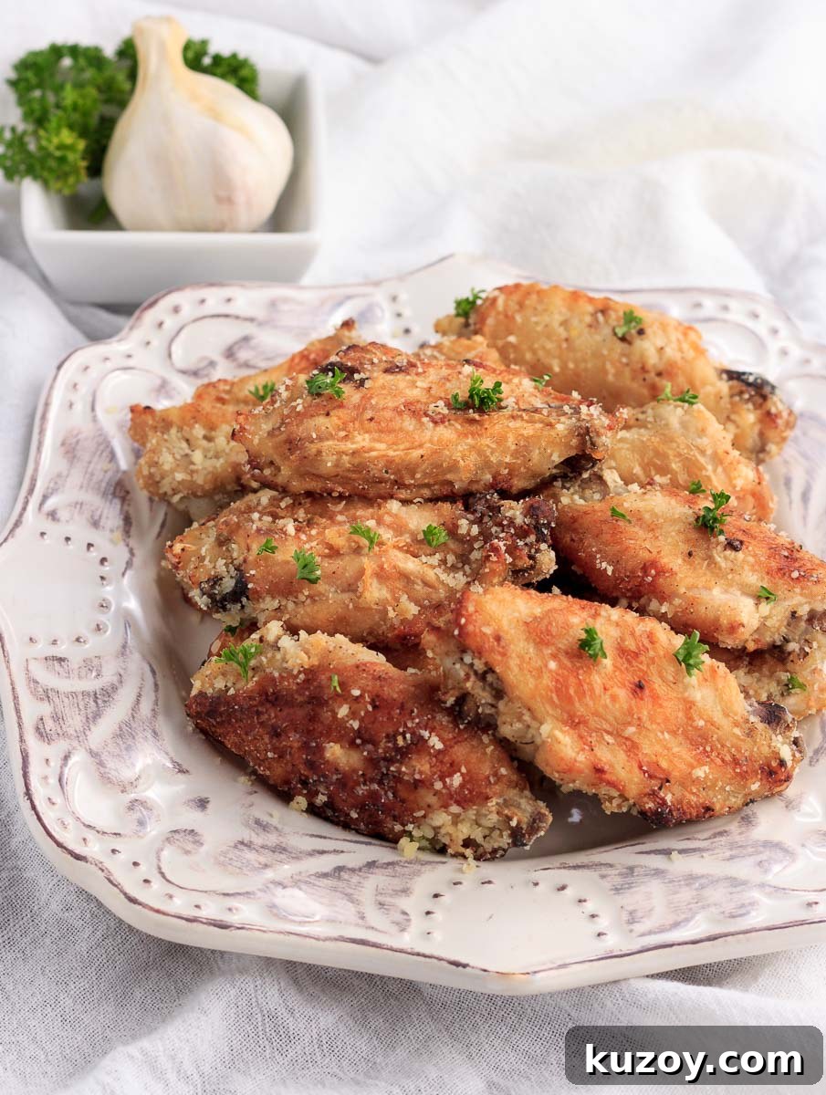 Keto Garlic Parmesan Wings in the Air Fryer 4 A stacked plate of chicken wings with garlic & parmesan cheese.