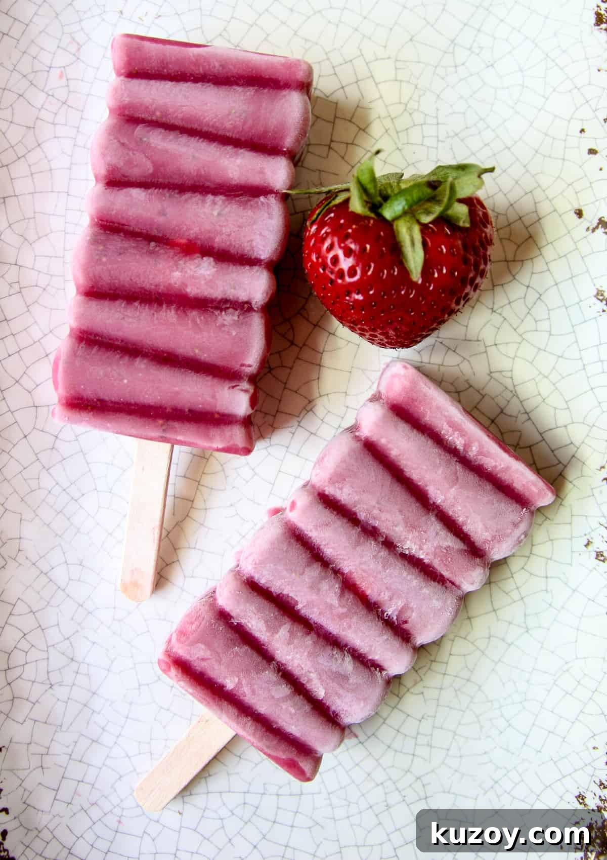 Sugar-Free Strawberry Popsicles Recipe — Fresh & Fruity 6 Homemade sugar free strawberry popsicles and a ripe strawberry on a speckled plate.