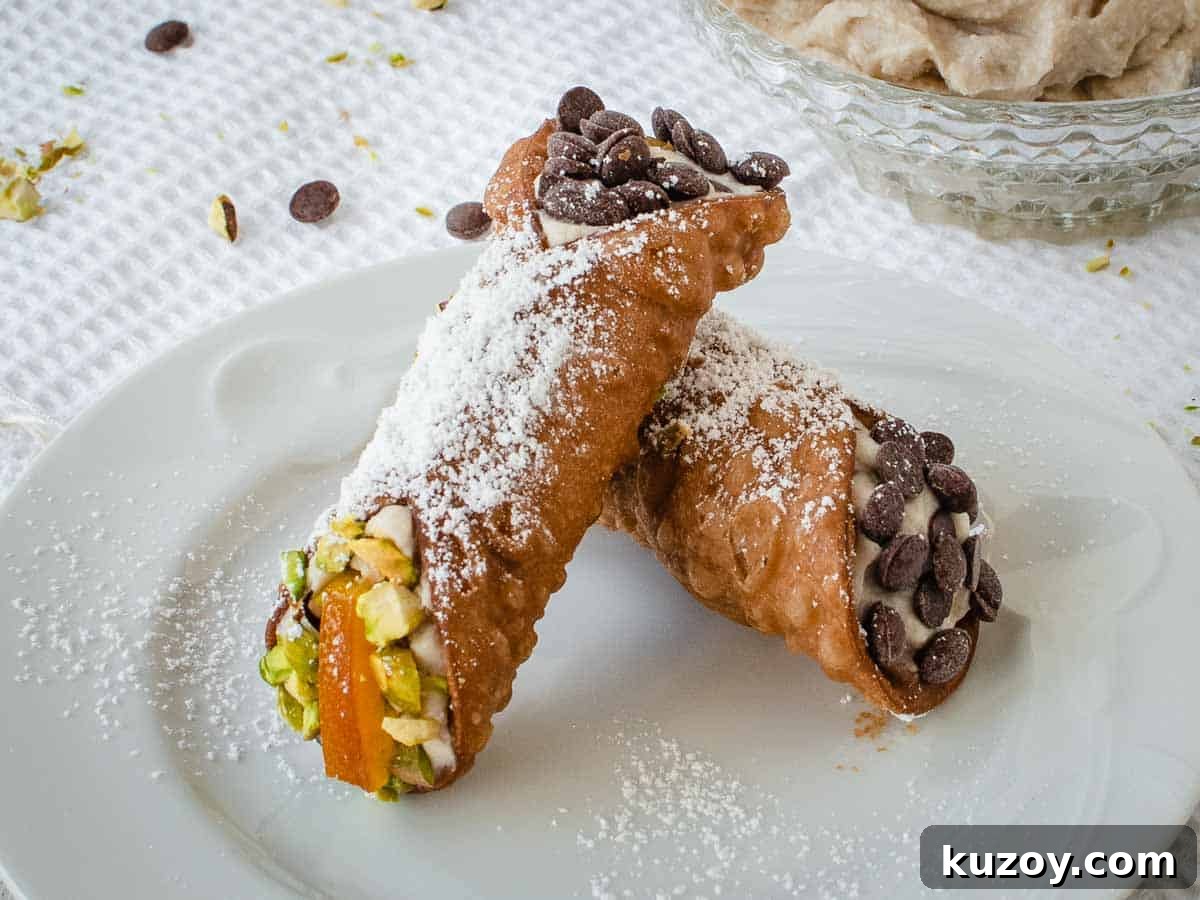 How to Make Classic Cannoli Filling at Home 7 Two filled cannoli resting on each other on a white plate.