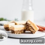 Carrot Cake Nanaimo Bars Recipe — Moist Spiced Dessert Bars 7 Sliced bars on a white plate with carrots and a jug of milk in the background