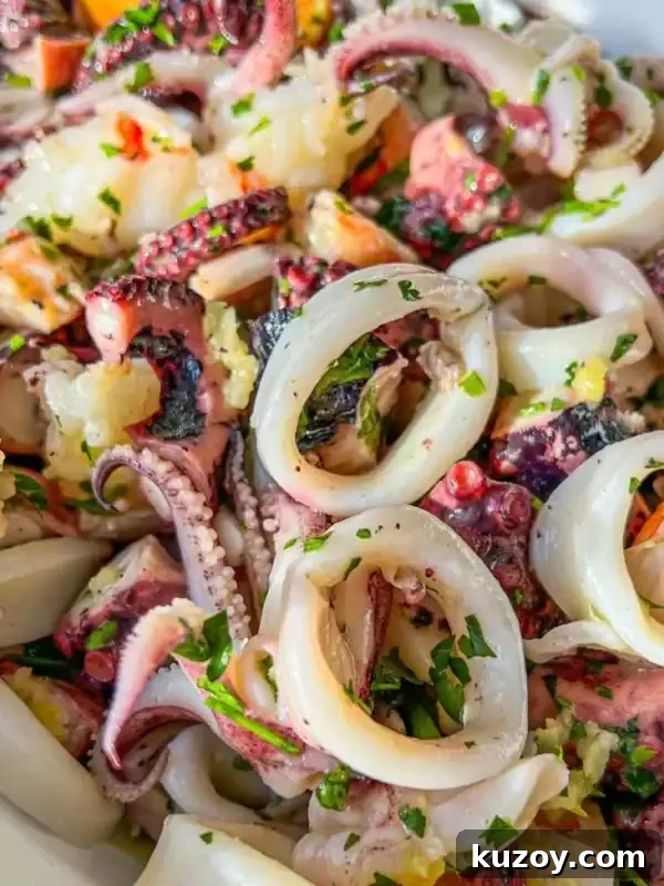 Fresh Seafood Salad Recipes: Light, Flavorful Ideas for Any Meal 3 Close-up of a seafood salad featuring rings and tentacles of octopus, garnished with chopped parsley and garlic, served in a white bowl.