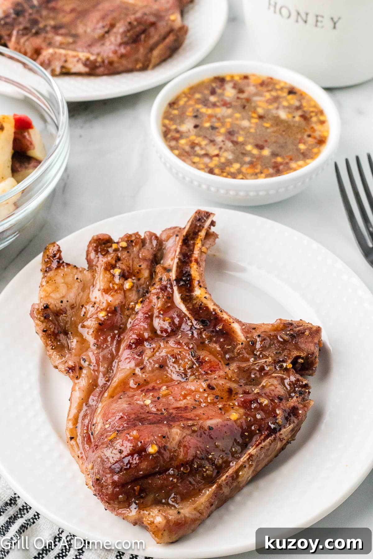 Spicy Honey-Glazed Pork Chops Recipe 2 Hot honey pork chops on a plate with a bowl of hot honey sauce on the side