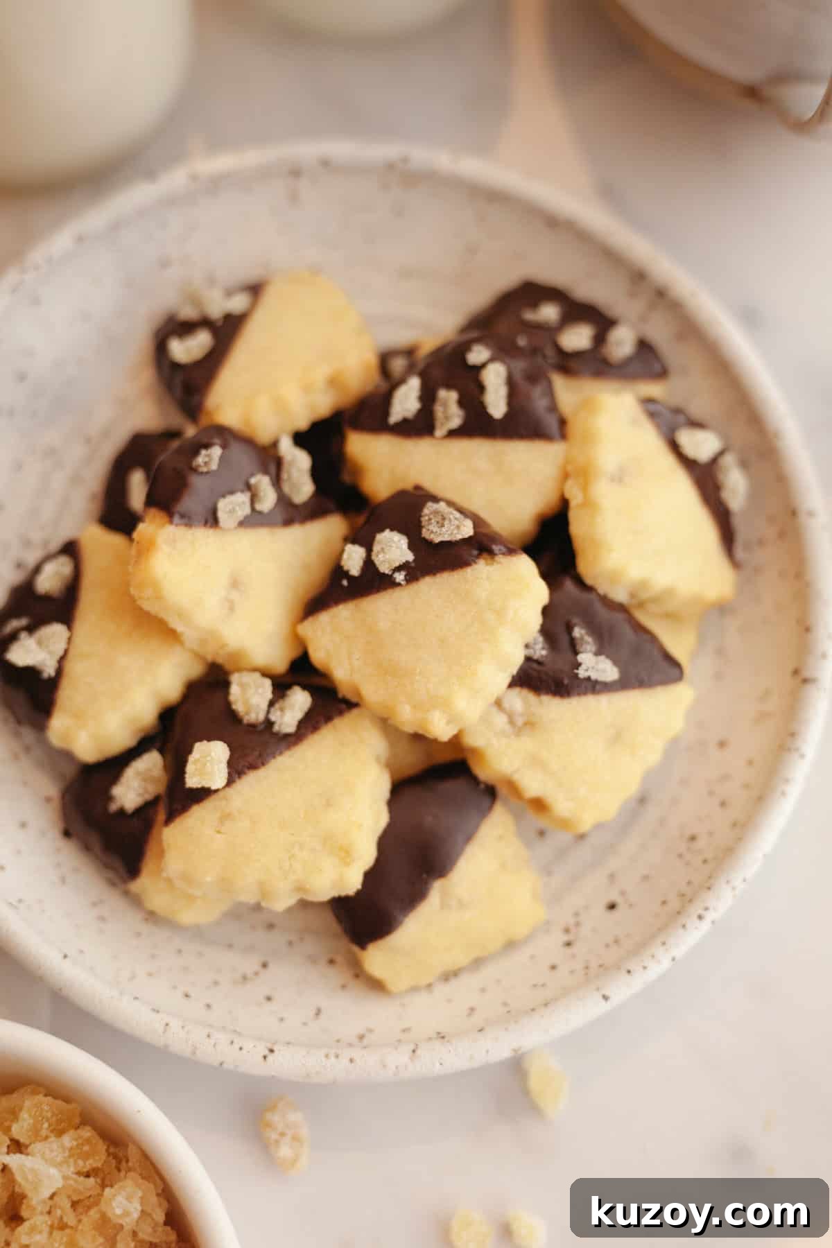 Double-Ginger Shortbread Cookies: Chewy Ginger & Crystallized Chip Recipe 11 A plate full of small ginger shortbread cookies, half dipped in chocolate.