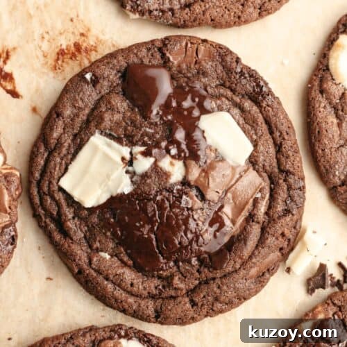 A close up of a triple chocolate chunk cookie on brown parchment paper.