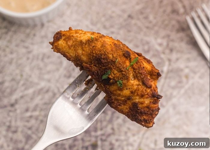 Crispy Air Fryer Blackened Chicken Tenders 3 Up close photo of piece of seasoned chicken on a fork garnished with parsley flakes.