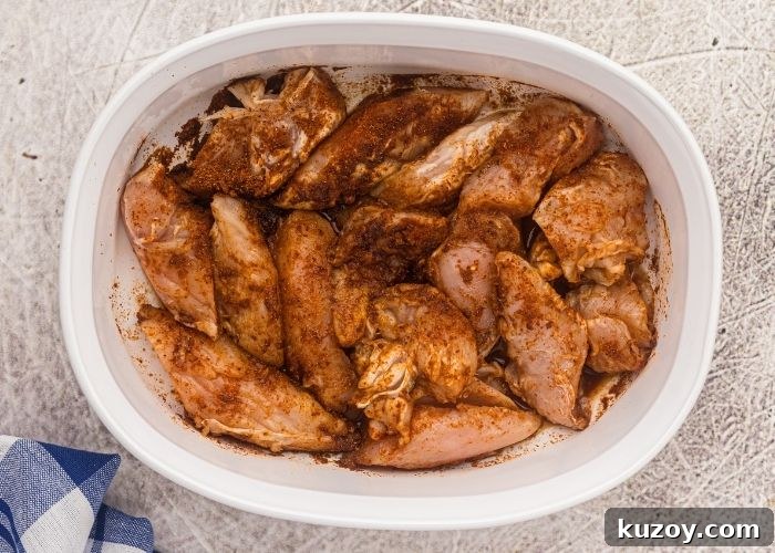 Crispy Air Fryer Blackened Chicken Tenders 4 Seasoned raw chicken tenders in a white oblong dish, before cooking in the air fryer.