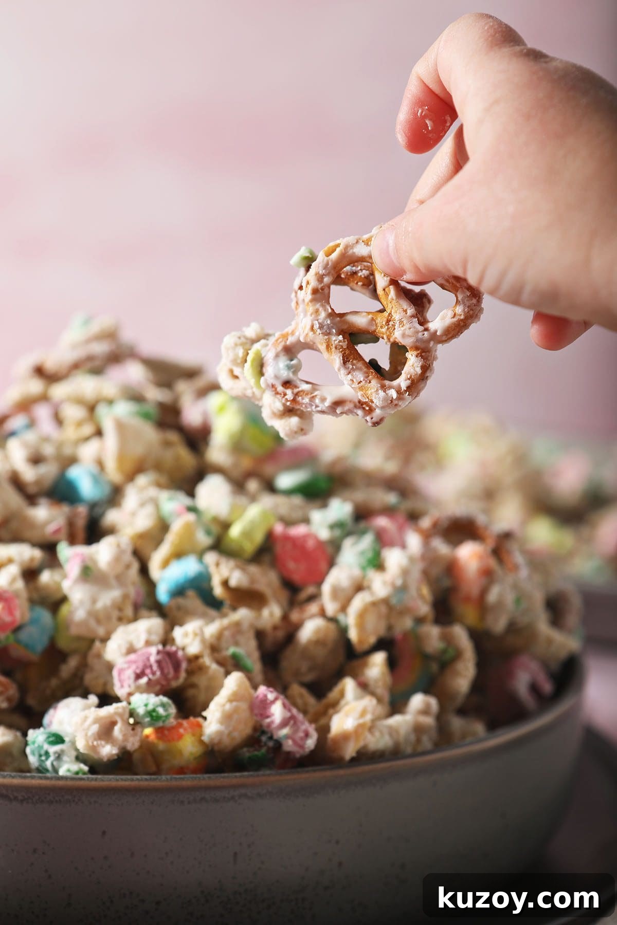 St. Patrick’s Day Snack Mix Recipe for Festive Parties 7 A child lifts a pretzel out of a bowl of snack mix for St. Patrick's Day