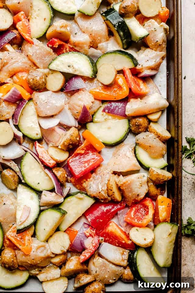 One-Pan Roasted Chicken with Seasonal Vegetables 3 prepping raw chicken and vegetables on a baking sheet