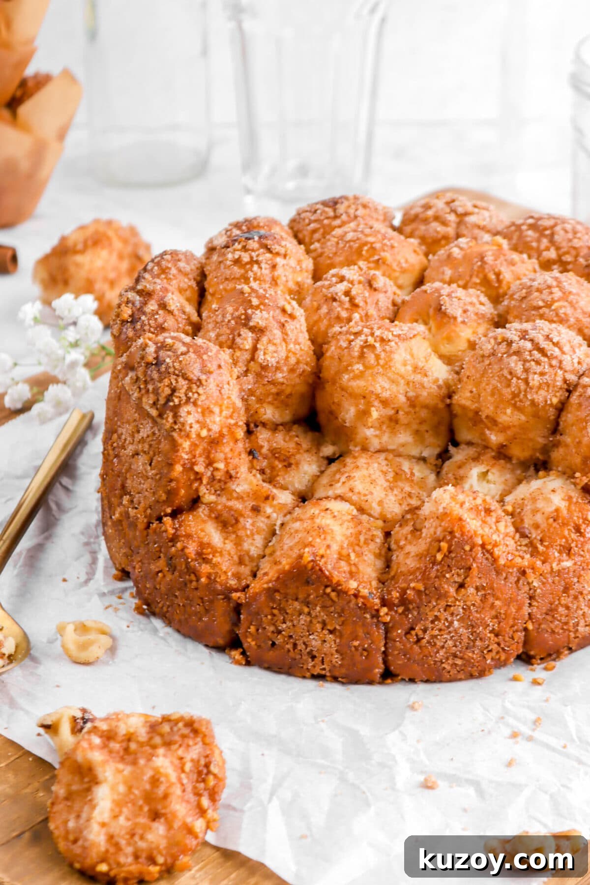 Cinnamon Sugar Walnut Pull-Apart Bread Recipe 3 angled close up of cinnamon sugar pull apart bread with pieces missing on parchment paper
