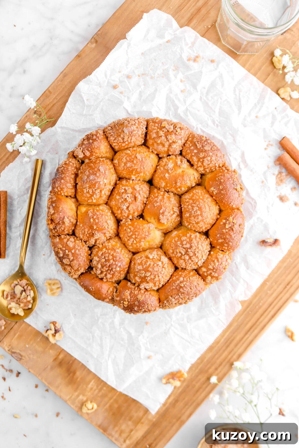 Cinnamon Sugar Walnut Pull-Apart Bread Recipe 4 overhead shot of bread on parchment paper on wood board with gold spoon beside and flowers