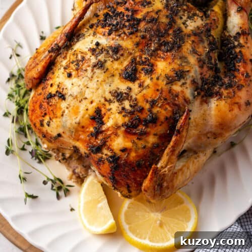 An herb roasted chicken on a white serving platter.