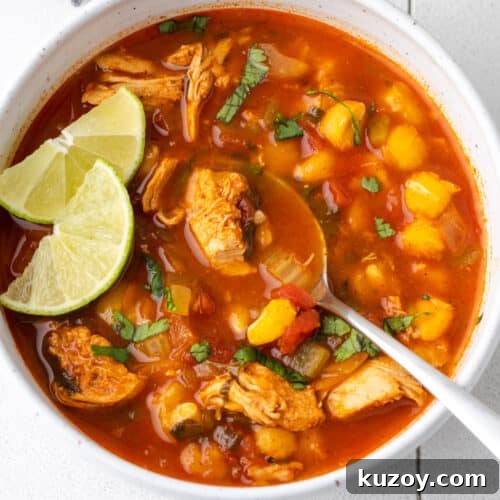 A bowl of chilis southwest chicken soup topped with cilantro and lime slices.