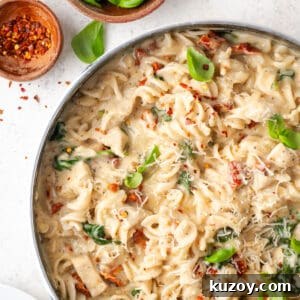 30-Minute Marry Me Chicken Pasta Recipe for Date Night 19 A pan filled with marry me chicken pasta sitting on a white table.