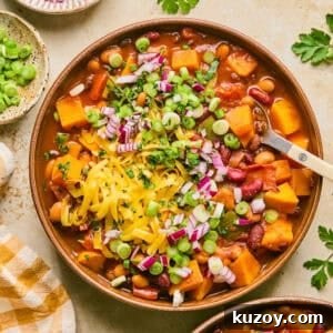 Hearty Butternut Squash & White Bean Chili Recipe 9 Overhead view of bowl with butternut squash chili with spoon scooping into the bowl.