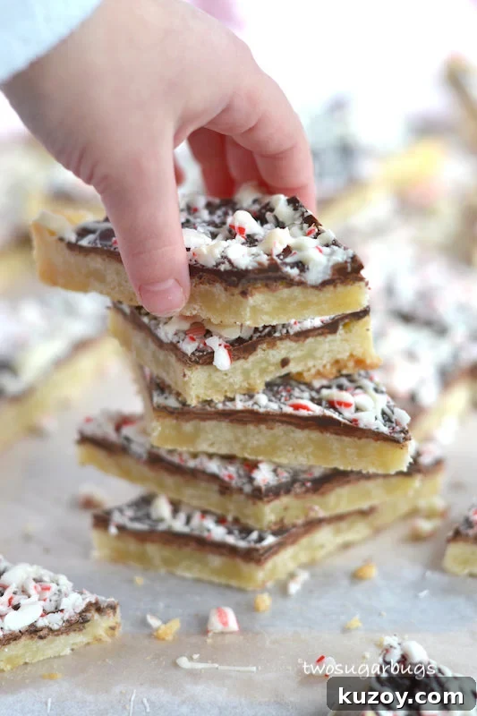 hand taking a cookie off the top of a stack of shortbread peppermint bark