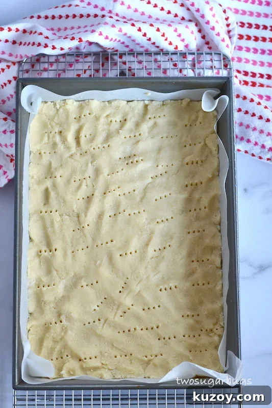 shortbread cookie dough in prepared pan with fork piercings