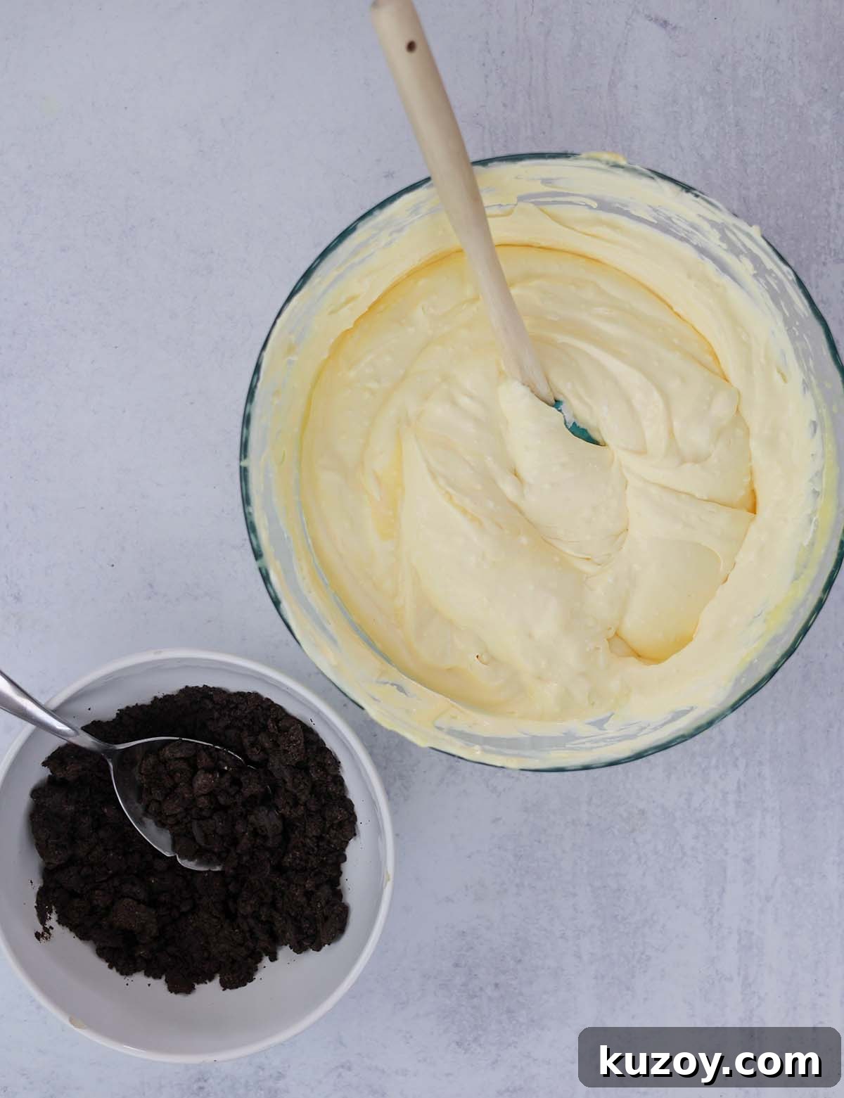 No-Bake Oreo Dirt Cake Recipe: Creamy, Crowd-Pleasing Dessert 4 pudding mixture in a bowl with a spoon and crushed Oreo cookies in a separate bowl with a spoon.