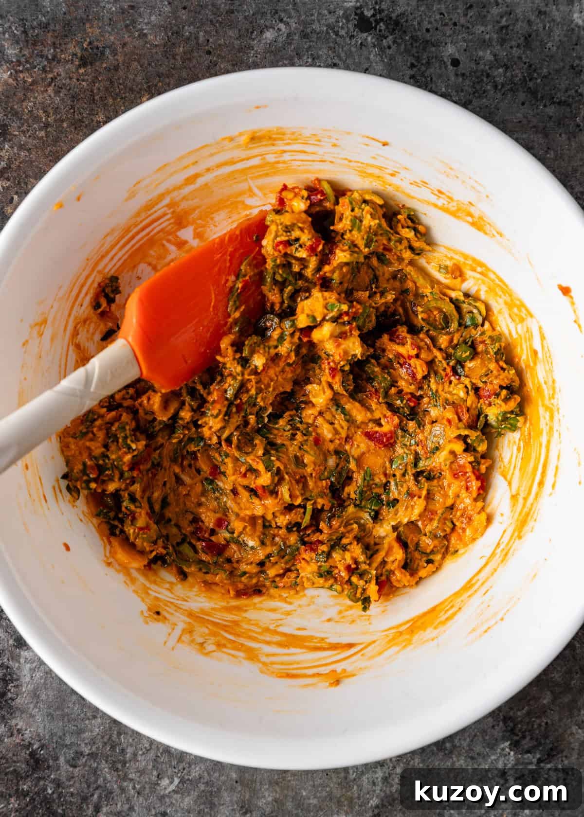 overhead process shot: combining the herb chili butter with a red spatula
