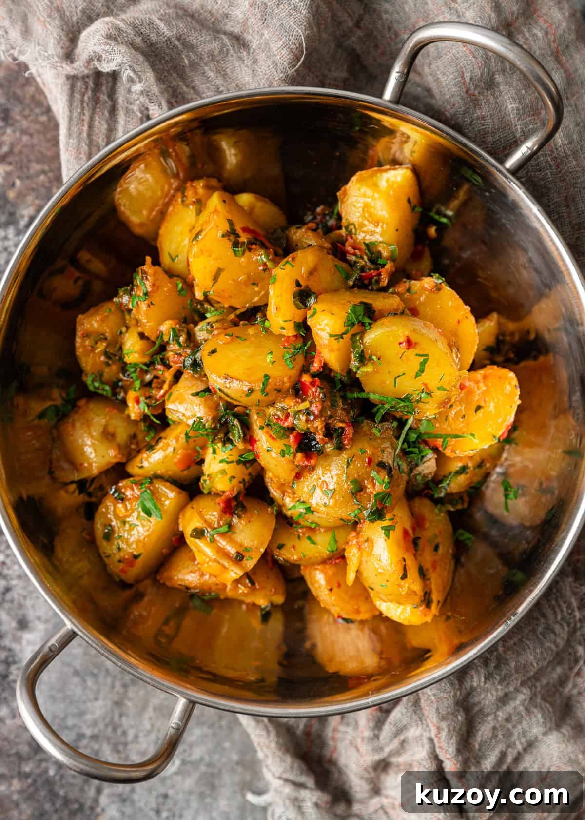 overhead: potatoes and peppers cooked in herb chili butter in a metal bowl