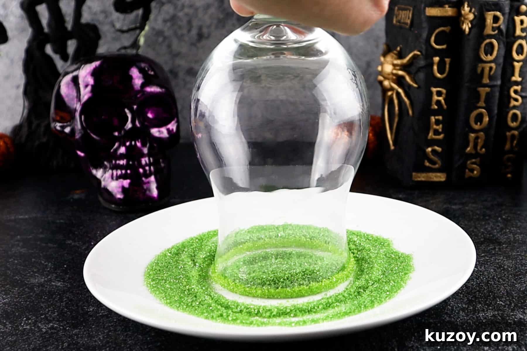Spooky Cauldron Cocktail Recipe for Halloween Parties 6 spinning glass rim in green sprinkles that are placed on a shallow white plate.
