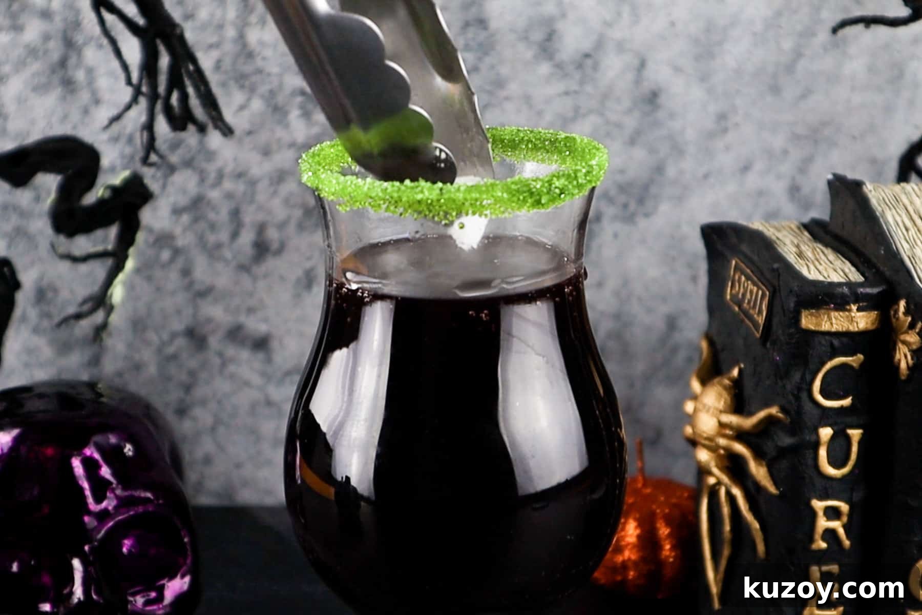 Spooky Cauldron Cocktail Recipe for Halloween Parties 8 adding dry ice to halloween drink using tongs.