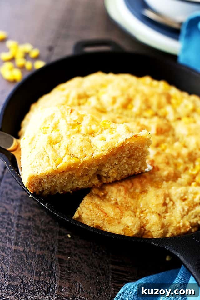 This skillet cornbread recipe is made from scratch and loaded with cheese and sweet corn. Crispy on the edges and fluffy on the inside! Cornbread being served from a skillet.
