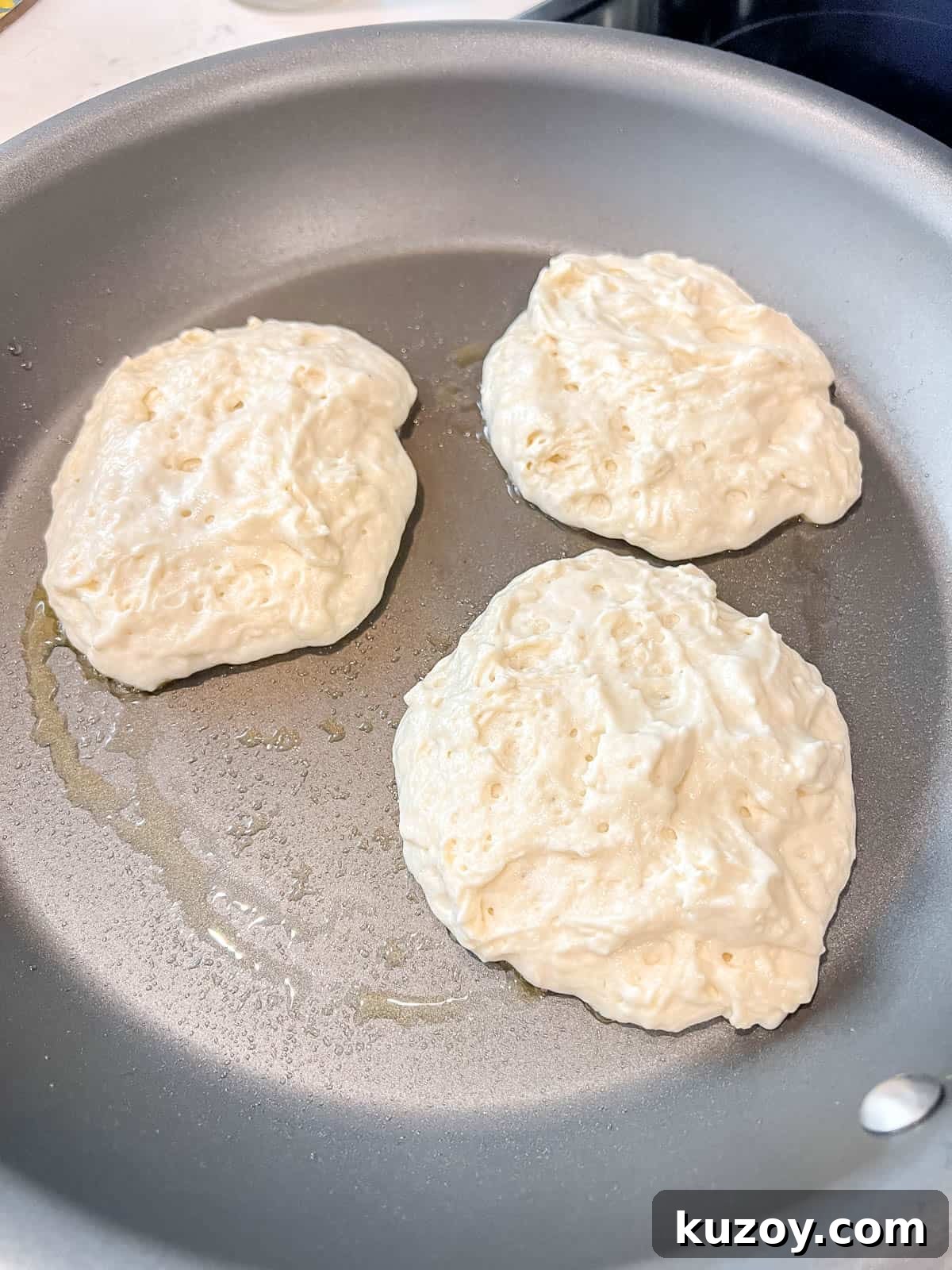 Fluffy Greek Yogurt Pancakes for Light, Protein-Packed Breakfast 7 Greek yogurt pancakes before flipping on a pan.