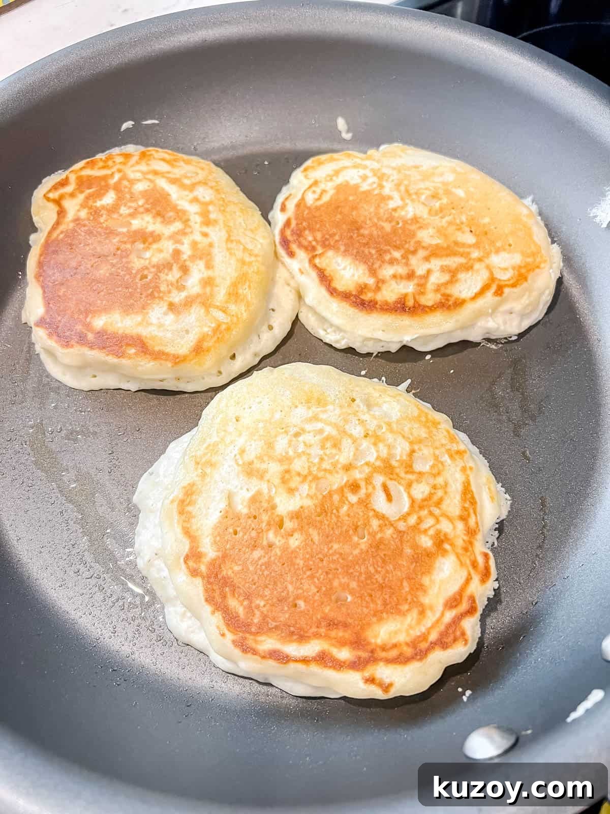 Fluffy Greek Yogurt Pancakes for Light, Protein-Packed Breakfast 8 Greek yogurt pancakes after flipping on a pan.