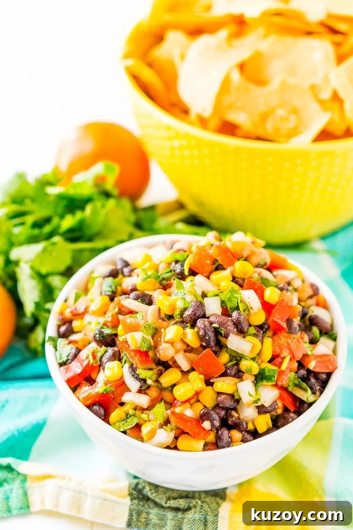 Zesty Cowboy Caviar Salad with Black Beans & Corn 3 Bowl of Cowboy Caviar with a bowl of tortilla chips in background on teal and yellow napkin.