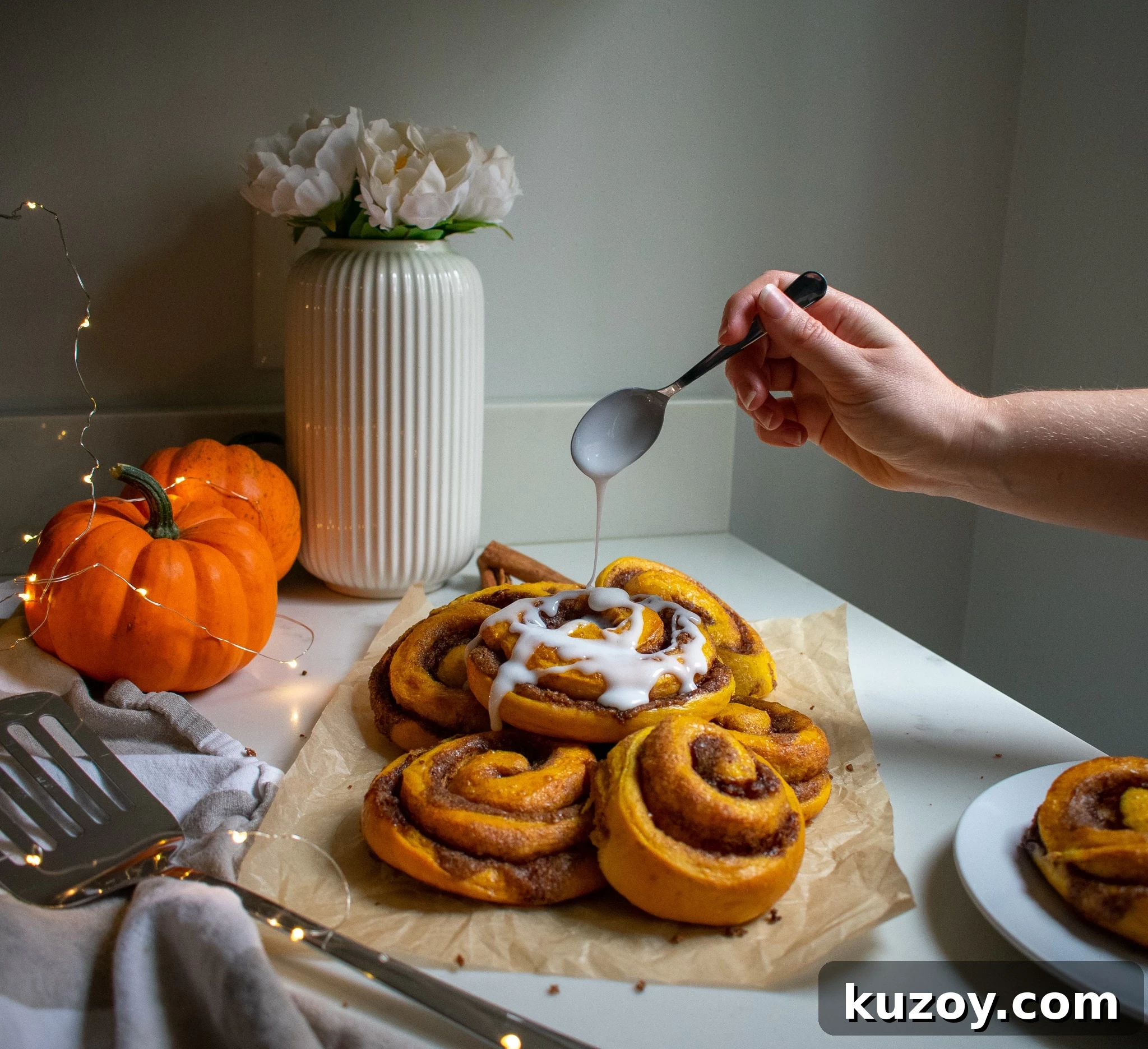 Pumpkin Spice Cinnamon Rolls with Spiced Sugar Glaze 3 A person putting icing on a cinnamon roll.