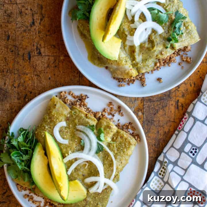 Two plates of vegan enchiladas topped with avocado and onions.