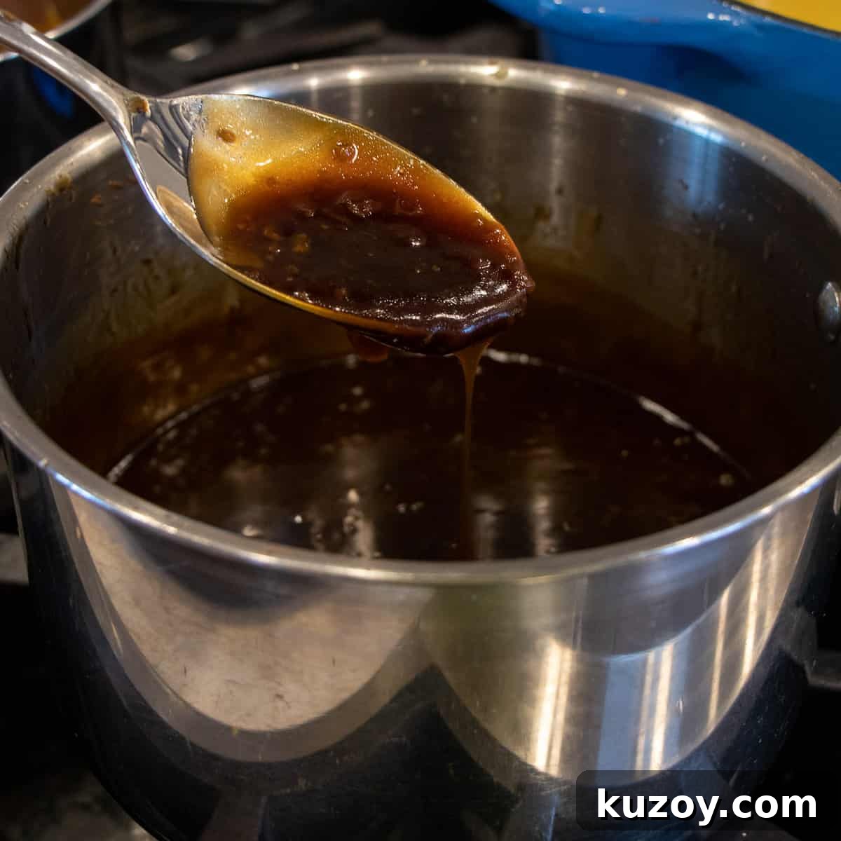 Sticky Honey Garlic Chicken Wings Recipe (Crispy & Flavorful) 5 A spoon of sauce lifted out of a saucepan.