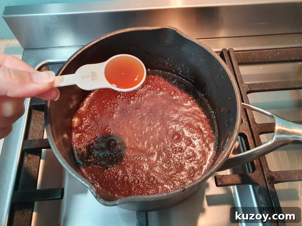 adding vanilla essence to pot on stove with chocolate fudge sauce ingredients.