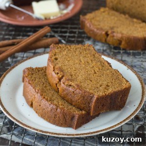 Copycat Starbucks Pumpkin Bread Recipe: Moist Loaf with Spices 8 Two slices of moist, golden brown pumpkin bread—just like the Starbucks Pumpkin Bread Recipe—sit on a white plate, with cinnamon sticks nearby and a plate of butter in the background.