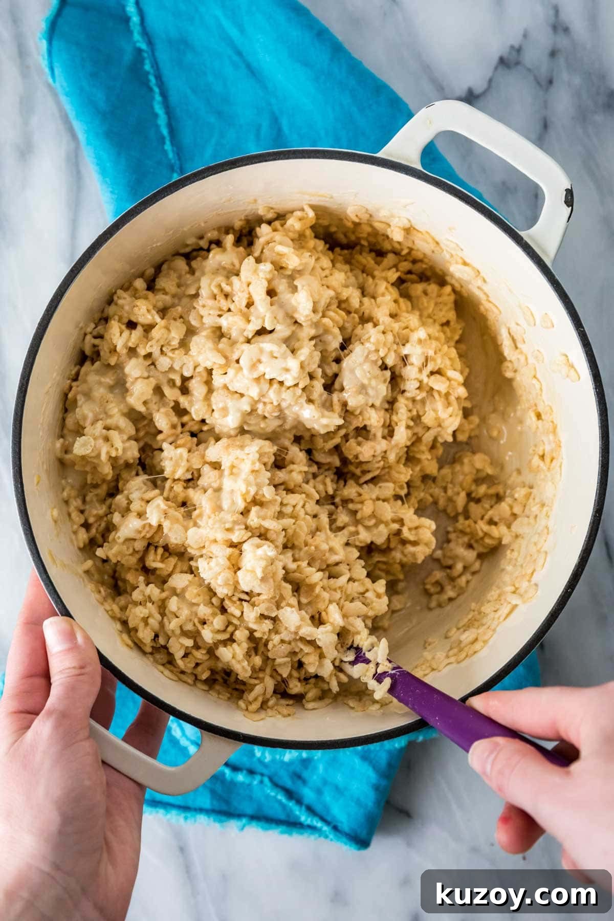 mixing cereal into a salted caramel sauce in a white Dutch oven