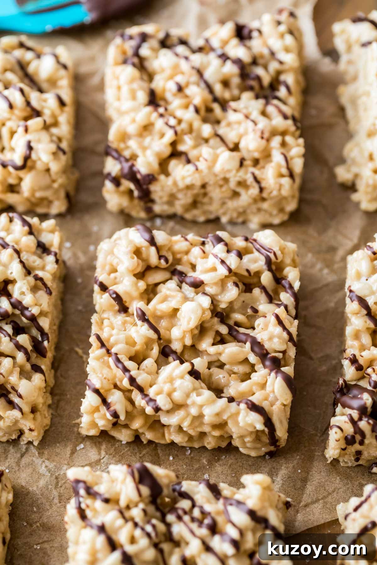 Rows of rice krispie treats topped with a chocolate drizzle.