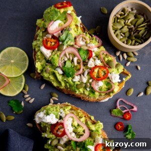 Creamy Avocado Toast with Lemon, Chili Flakes, and Crispy Sourdough 13 Two pieces of loaded avocado toast with feta, shallot, sliced red chilli, seeds and coriander (cilantro) on a dark grey background. There are ingredients scattered around and a pinch pot of seeds in the top right corner.