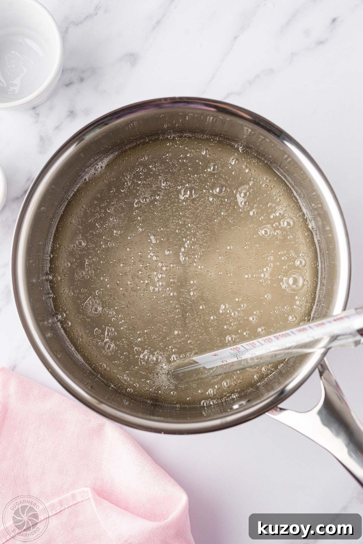 How to Make Smooth Homemade Caramel Sauce for Desserts 13 A pot of bubbling caramel sauce with a thermometer in it.
