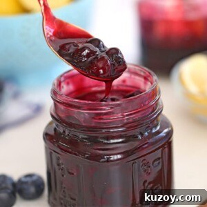 How to Make Smooth Homemade Caramel Sauce for Desserts 8 Close up of blueberry sauce in a glass mason jar with a spoonful of blueberry sauce hovering over the jar.